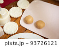 Female hands making dough for mooncake, homemade cantonese moon cake pastry on baking tray before baking for traditional festival. Travel, holiday, food concept 93726121