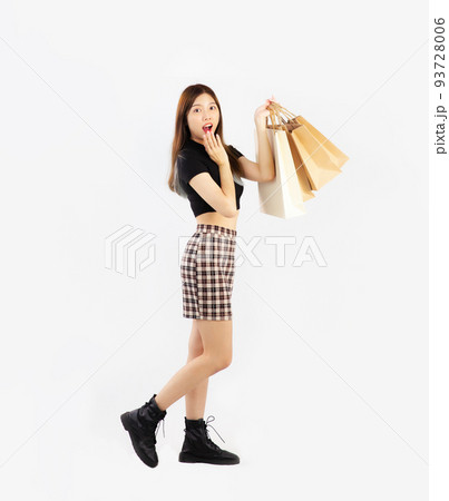 Young asian woman in black crop t-shirt carrying brown paper shopping bags, full body posing on white background. 93728006