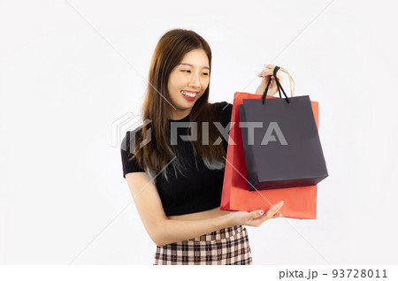 Young asian woman long hair in black t-shirt carrying and holding black and red paper shopping bags on white background. 93728011