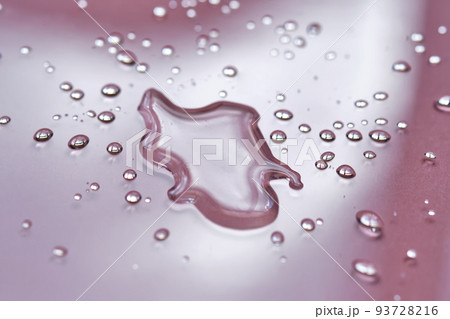 A large drop and splashes of micellar water on a pink background. A large drop and splashes of micellar water on a pink background. 93728216