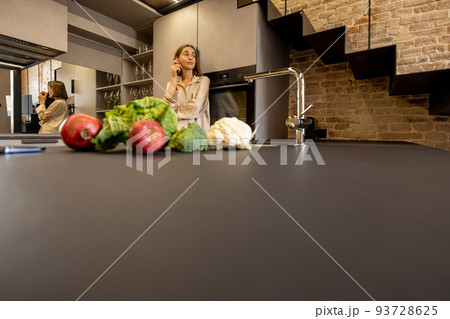Fresh food ingredients on a kitchen table and woman on background Fresh food ingredients on a kitchen table and woman on background 93728625