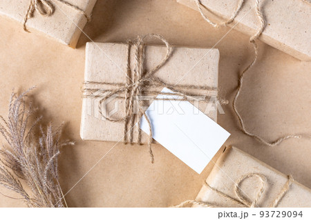 empty white gift tag mock up on craft paper box with dried spikelets decoration on natural beige background. 93729094