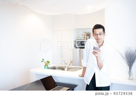 ダイニングで仕事の傍ら、血流を促進させつつスマホで情報収集をしている男性 93729336