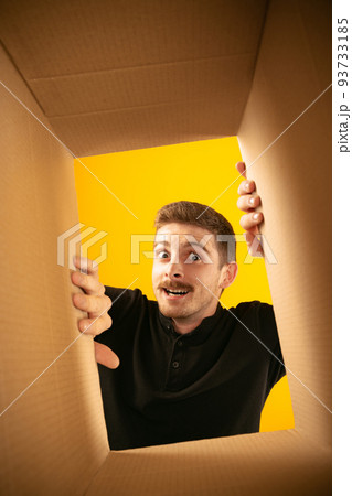 Surprising man unpacking opening carton box and looking inside. Delivery, surprise, gift, wow emotions concept. Black friday, holidays, online shopping 93733185