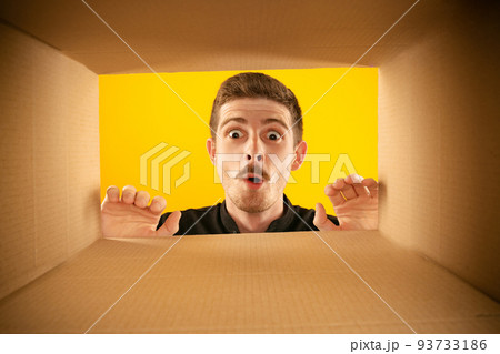 Wow. Surprised man unpacking, opening carton box and looking inside with wide open eyes. Delivery, surprise, gift, wow emotions concept. 93733186