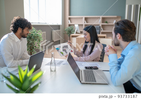 Two men and woman working in the office and looking involved 93733187