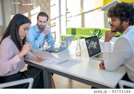 Two men and woman working in the office and looking involved 93733188