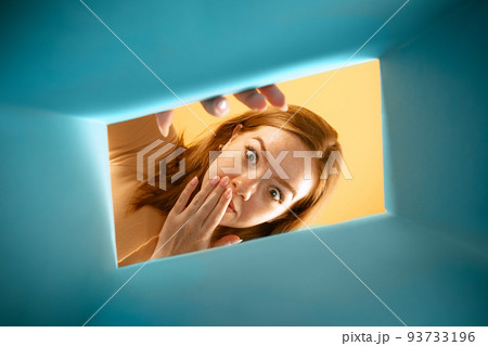 Beautiful young exressive girl opening, unpacking carton box and looking inside. Emotions, black friday, holidays, online shopping concept 93733196