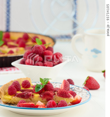 Round quiche with red strawberries and raspberries on a white table 93734105