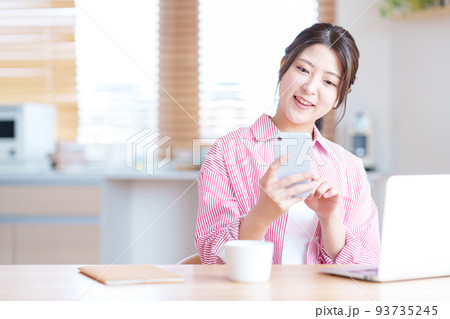 リビングでネットショッピングをする若い女性 93735245
