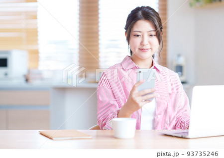 リビングでネットショッピングをする若い女性 リビングでネットショッピングをする若い女性 93735246