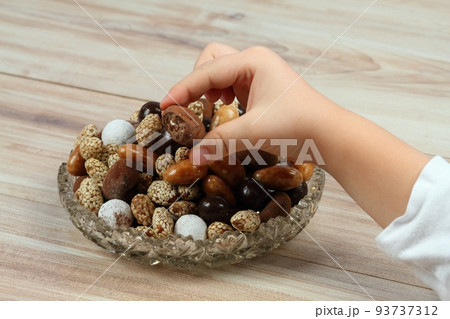 Child hand taking assorted chocolate and coated candies Child hand taking assorted chocolate and coated candies 93737312