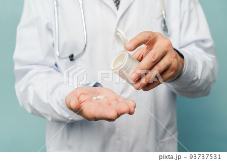 Doctor pouring pills on his palm 93737531