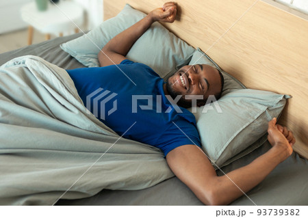 Happy Black Male Stretching After Good Sleep Lying In Bedroom 93739382