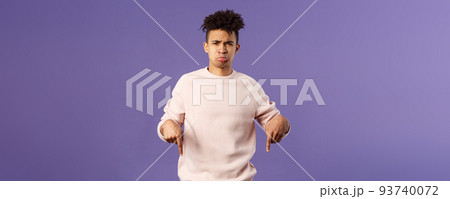 Portrait of upset and disappointed man talking about his bad experience with awful app, sulking and frowning offended, feel uneady and distressed, pointing fingers down dissatisfied 93740072