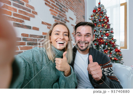 Woman and man at home looking at smartphone camera greet friends with holidays, young family during New Year holidays and Christmas 93740880