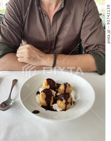 man eating profiteroles at a restaurant table man eating profiteroles at a restaurant table 93742139