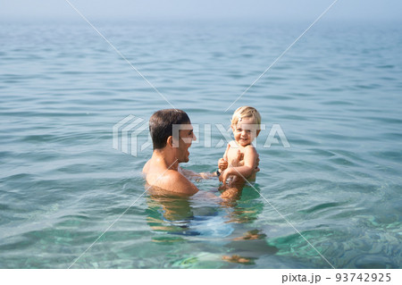 Dad bathes with a little daughter in his arms in the sea 93742925