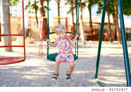 Little girl sits on a swing and looks away 93742937