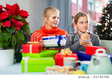 Mom and daughter unpack gifts during christmas Mom and daughter unpack gifts during christmas 93746766