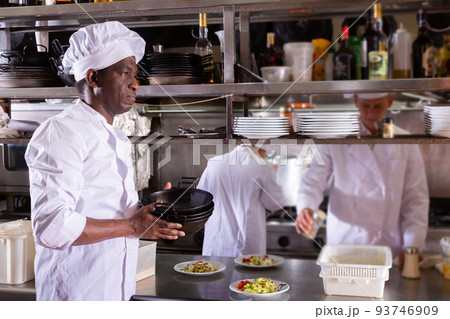 Professional african american cook working in kitchen of restaurant Professional african american cook working in kitchen of restaurant 93746909