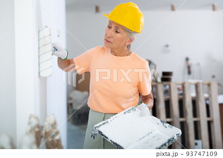 Mature woman painting wall, diy renovating home 93747109