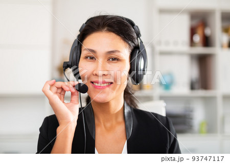 Smiling young female operator talking with customer using headset at office 93747117