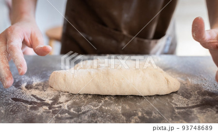 The process of making traditional French baguettes. Forming a blank from the dough. Front view. The process of making traditional French baguettes. Forming a blank from the dough. Front view. 93748689
