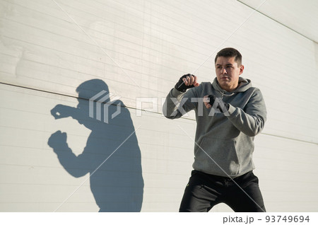 Caucasian man in hoodie is training boxing outdoors. Caucasian man in hoodie is training boxing outdoors. 93749694