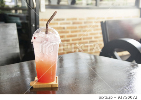 Iced Strawberry soda with straw in plastic cup on table. Iced Strawberry soda with straw in plastic cup on table. 93750072