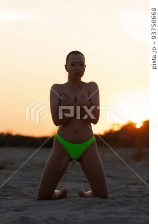 Young alluring topless woman covering naked breast on sandy seashore Young alluring topless woman covering naked breast on sandy seashore 93750668
