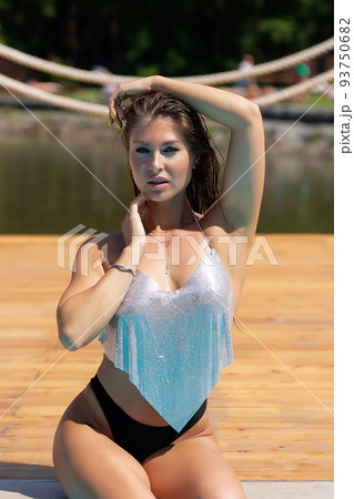 Alluring woman touching face and looking at camera at poolside Alluring woman touching face and looking at camera at poolside 93750682