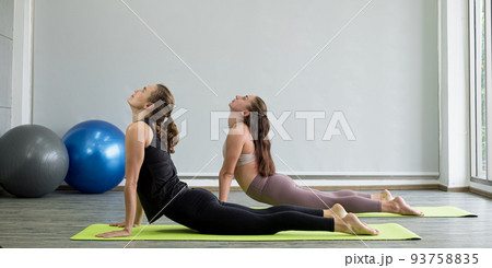 Two young women play yoga stretching, exercise for health in fitness, the concept of physical and mental health care Two young women play yoga stretching, exercise for health in fitness, the concept of physical and mental health care 93758835