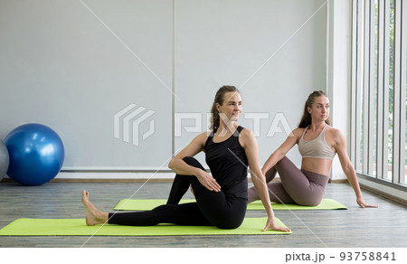 Two young women play yoga stretching, exercise for health in fitness, the concept of physical and mental health care Two young women play yoga stretching, exercise for health in fitness, the concept of physical and mental health care 93758841
