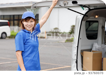 軽バンのバックドアを女性が開けると段ボールが積まれている。軽自動車や軽貨物の運転手。 93760070