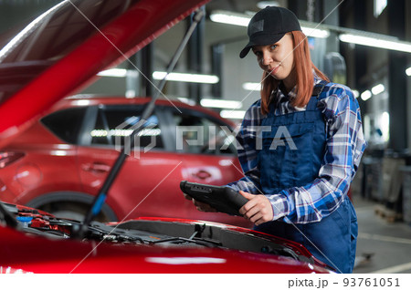 Caucasian female auto mechanic uses a special computer to diagnose faults.  93761051