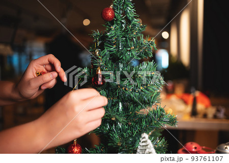 person hand decorating green festive christmas tree at new year eve 93761107