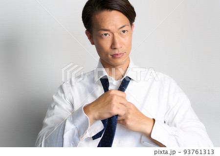 前を見ながらネクタイを結ぶビジネスマン 93761313