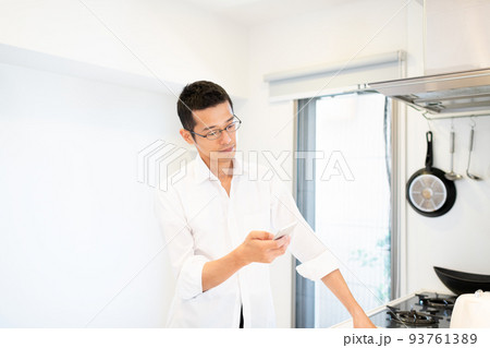 キッチンでスマホを使って調べ物をしている男性 93761389