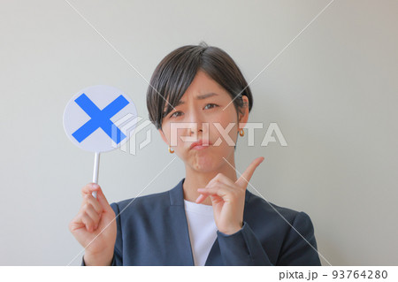 Xのプレートを持ち人差し指を立てる女性2 93764280