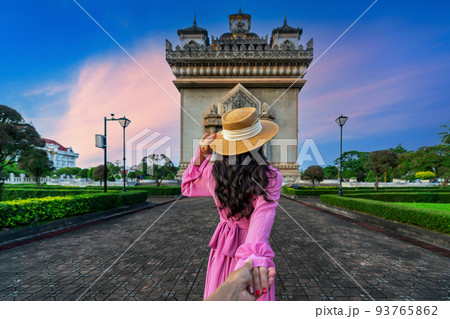 Women tourists holding man's hand and leading him to Patuxai in Vientiane, Laos. Women tourists holding man's hand and leading him to Patuxai in Vientiane, Laos. 93765862