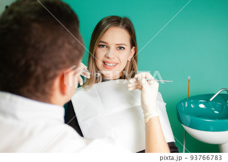Dentist examines teeth of his patient. Attractive girl is being examined by a dentist.. Dentist examines teeth of his patient. Attractive girl is being examined by a dentist.. 93766783