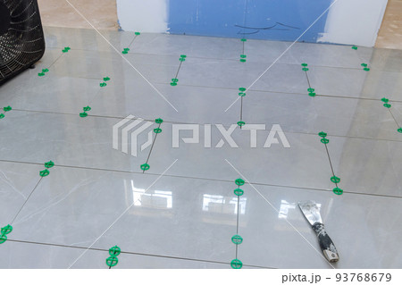 Currently under construction is a new house that has laying ceramic tiles in the bathroom 93768679