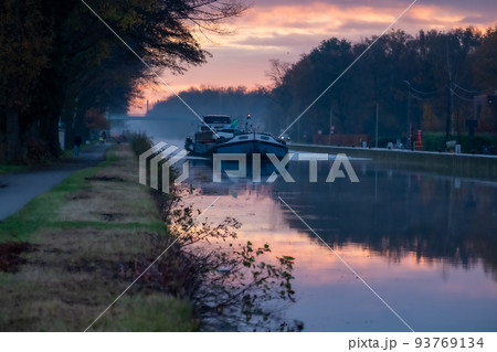 Cargo ship on a river during a misty sunrise morning Cargo ship on a river during a misty sunrise morning 93769134
