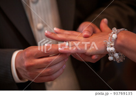 Close up of loving bride and groom putting a beautiful wedding ring to the beloved partner, marry me Close up of loving bride and groom putting a beautiful wedding ring to the beloved partner, marry me 93769135