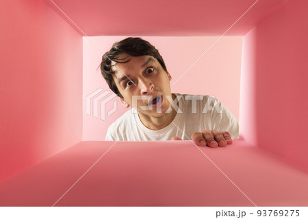 Young emotive man looking inside carton box with shocked expression Young emotive man looking inside carton box with shocked expression 93769275