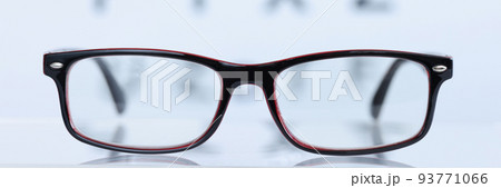 Glasses in black frame lying on background of eye test table closeup 93771066