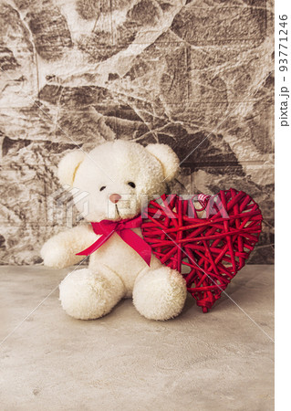 White Teddy bear with red heart on grey wall background 93771246
