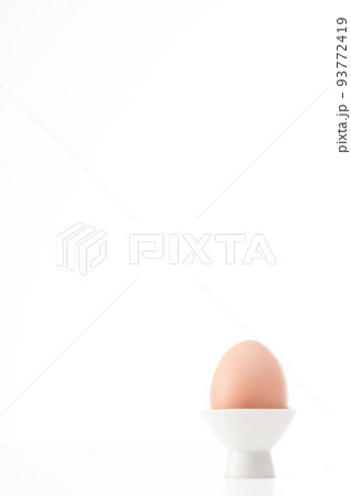 boiled chicken egg in its cup on white background 93772419