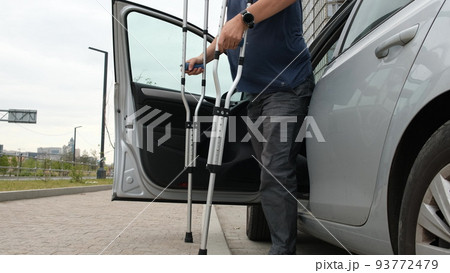 Man with leg injury comes out of car wash using crutches 93772479